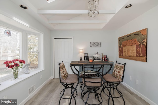 dining space with beam ceiling, baseboards, visible vents, and light wood finished floors