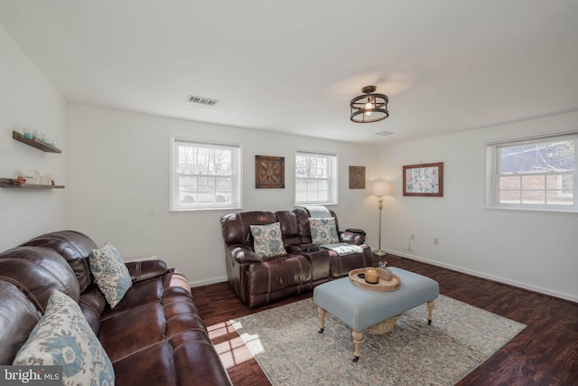 living room with wood finished floors, visible vents, and baseboards