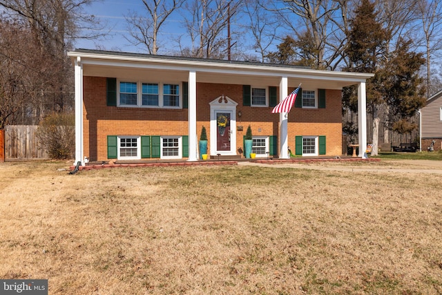 raised ranch featuring brick siding and a front lawn