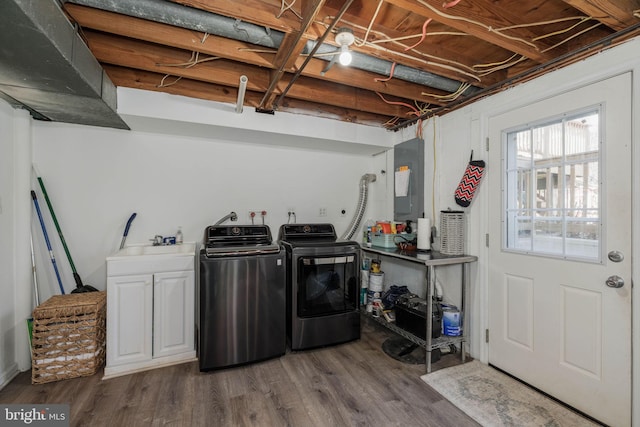 laundry room featuring dark wood-style flooring, washer and clothes dryer, cabinet space, a sink, and electric panel