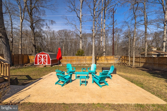 view of patio / terrace featuring a storage shed, a fenced backyard, a fire pit, and an outbuilding