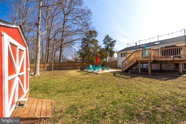 view of yard featuring an outbuilding, a fenced backyard, stairs, a wooden deck, and a patio area