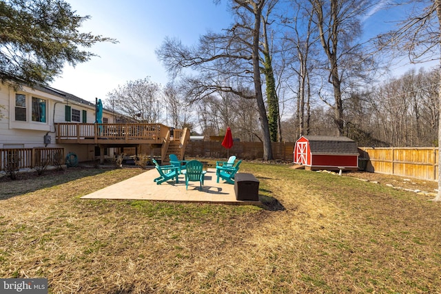 view of yard featuring an outbuilding, a patio, a shed, a fenced backyard, and a wooden deck