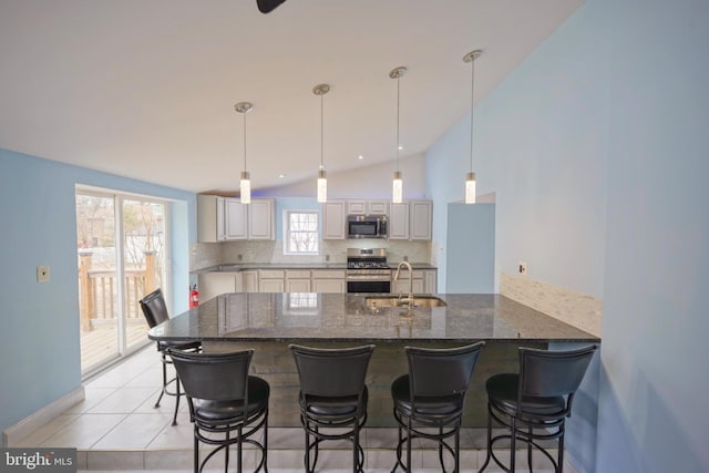 kitchen featuring light tile patterned floors, decorative backsplash, appliances with stainless steel finishes, a peninsula, and a sink