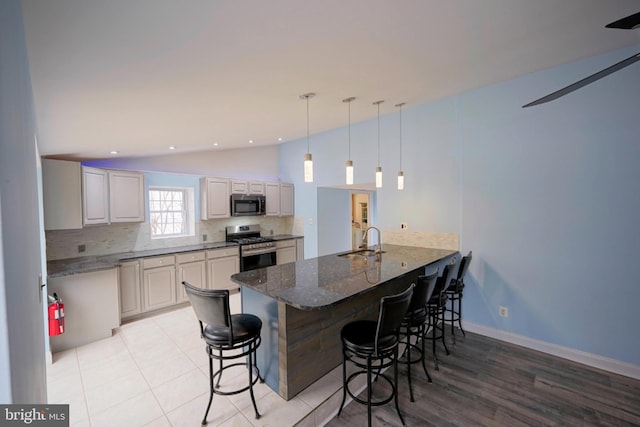 kitchen with appliances with stainless steel finishes, lofted ceiling, a sink, and a peninsula