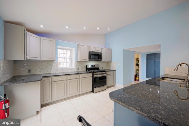 kitchen featuring lofted ceiling, a sink, stainless steel gas stove, tasteful backsplash, and dark stone countertops