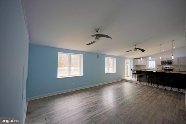 unfurnished living room featuring lofted ceiling, dark wood finished floors, a ceiling fan, and baseboards