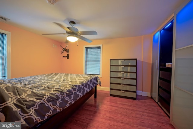 bedroom featuring ceiling fan, visible vents, baseboards, and wood finished floors