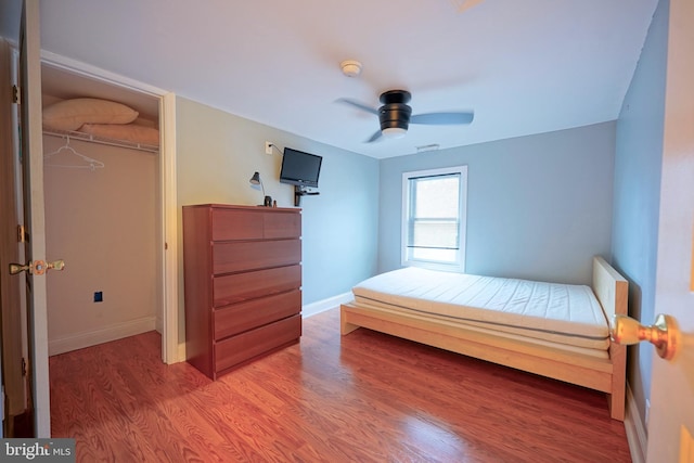 bedroom with a ceiling fan, a closet, baseboards, and wood finished floors