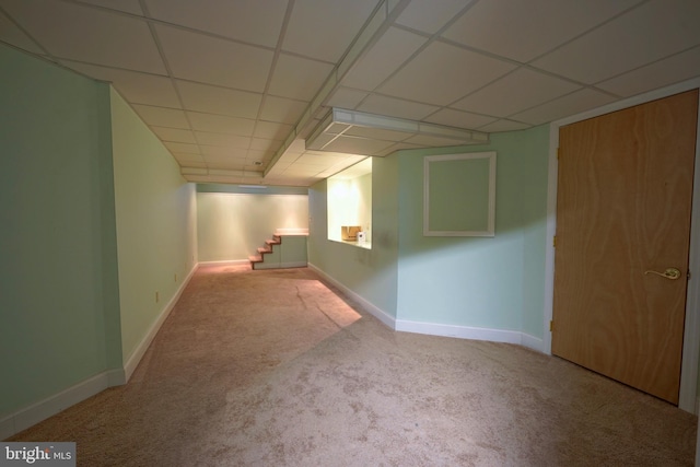 finished basement featuring baseboards, stairway, and a drop ceiling