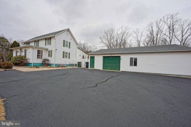 view of front of home with a garage, aphalt driveway, and an outdoor structure