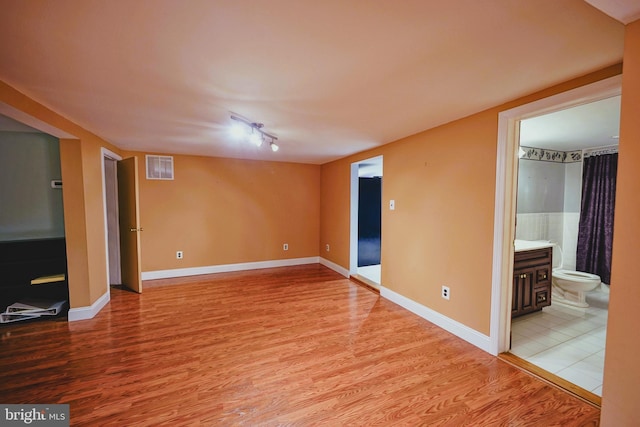 unfurnished room featuring light wood finished floors, visible vents, and baseboards