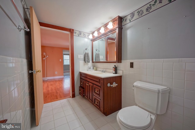 bathroom with toilet, vanity, tile walls, and tile patterned floors