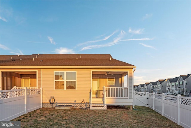 back of property with a residential view, a fenced backyard, and a lawn