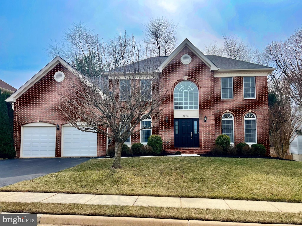 view of front facade with a front yard, brick siding, a garage, and driveway