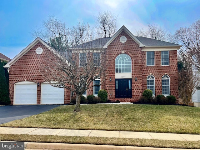 view of front facade with a front yard, brick siding, a garage, and driveway