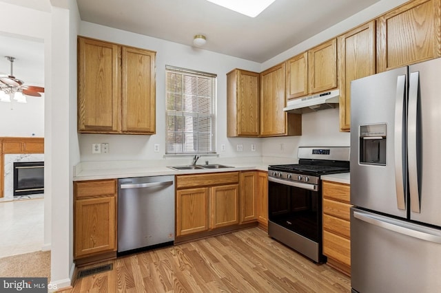 7315 Serenade Cir, Clinton, MD 20735 - kitchen with appliances with stainless steel finishes, under cabinet range hood, a sink, a fireplace, and light countertops