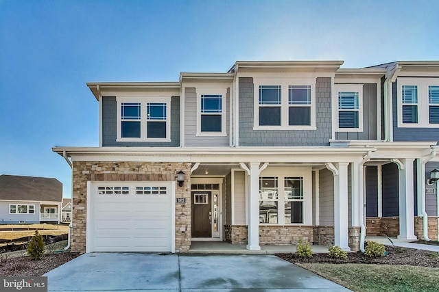 view of front of house featuring stone siding, covered porch, driveway, and an attached garage