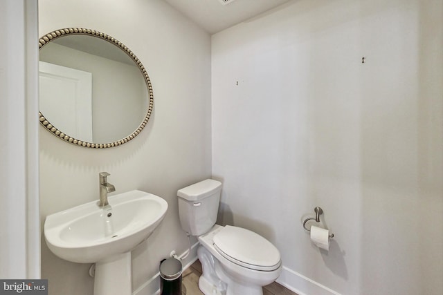 bathroom featuring baseboards, a sink, and toilet