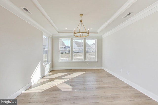 unfurnished dining area with ornamental molding, a tray ceiling, visible vents, and light wood-style flooring