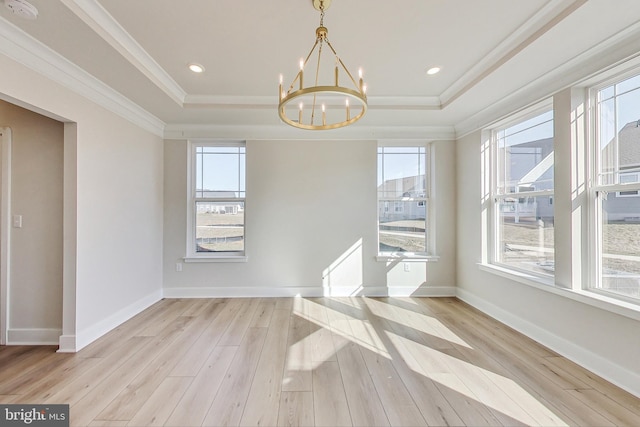 unfurnished dining area with wood finished floors, baseboards, ornamental molding, a tray ceiling, and an inviting chandelier