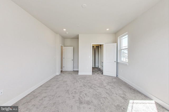 unfurnished bedroom with carpet floors, recessed lighting, a walk in closet, and baseboards