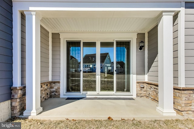 entrance to property with covered porch and stone siding