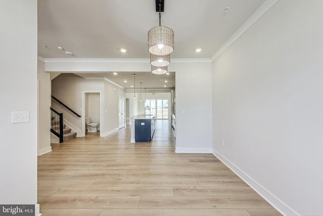 unfurnished dining area featuring baseboards, stairs, crown molding, light wood-style floors, and a sink