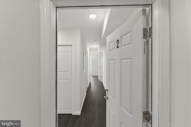 hallway with baseboards and dark wood-type flooring