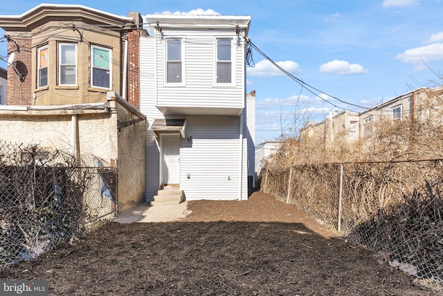 rear view of house featuring entry steps and a fenced backyard