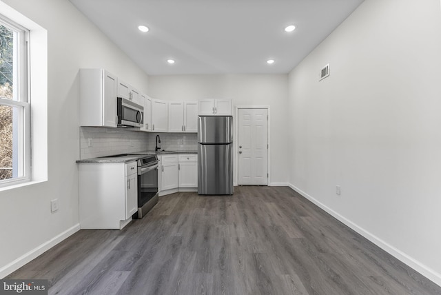 kitchen with appliances with stainless steel finishes, plenty of natural light, white cabinetry, and decorative backsplash