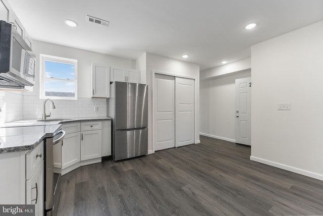 kitchen with a sink, visible vents, white cabinets, appliances with stainless steel finishes, and dark wood finished floors