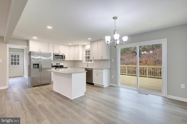 kitchen with visible vents, appliances with stainless steel finishes, light wood-style floors, a notable chandelier, and a sink