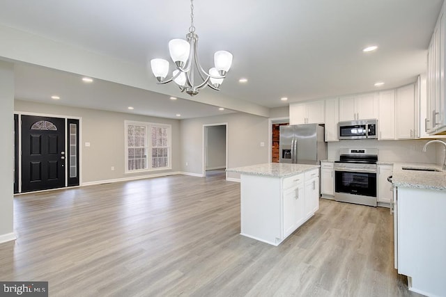 kitchen with a notable chandelier, light wood-style flooring, a kitchen island, recessed lighting, and stainless steel appliances