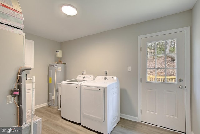 washroom featuring laundry area, light wood-type flooring, water heater, and washing machine and clothes dryer