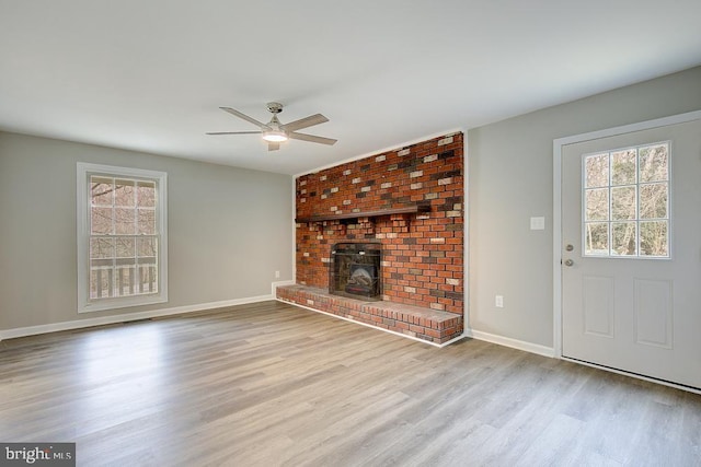 unfurnished living room featuring a wealth of natural light, baseboards, wood finished floors, and ceiling fan