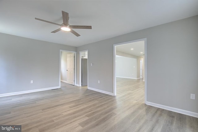 spare room featuring light wood-style flooring, baseboards, and ceiling fan