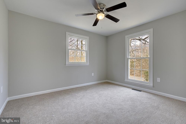 carpeted empty room featuring baseboards, visible vents, and ceiling fan