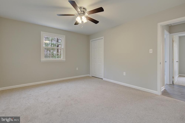 unfurnished bedroom featuring a ceiling fan, baseboards, a closet, and light carpet