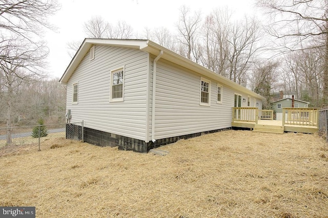 view of home's exterior with a deck and fence