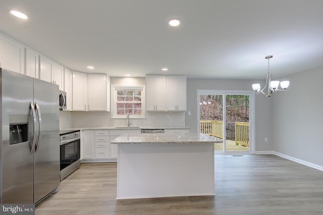 kitchen with a sink, decorative backsplash, appliances with stainless steel finishes, white cabinetry, and a chandelier