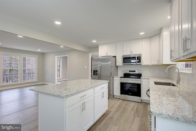 kitchen featuring light wood-style flooring, appliances with stainless steel finishes, white cabinets, and a sink