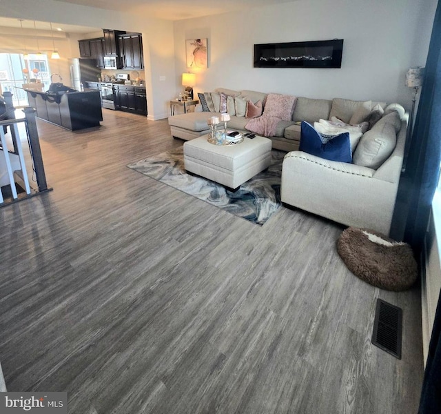 living room with visible vents, dark wood-type flooring, and baseboards