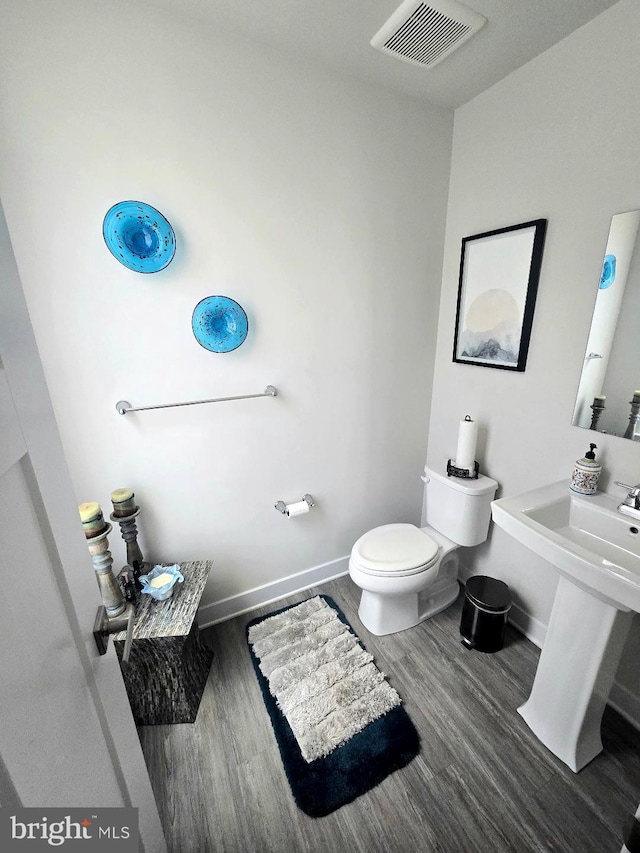 bathroom featuring toilet, wood finished floors, visible vents, and baseboards