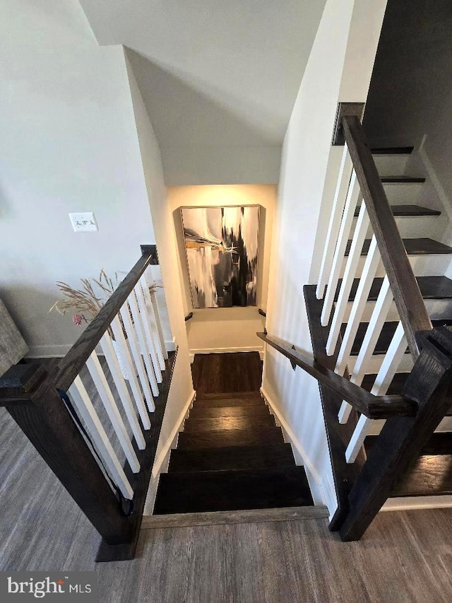 staircase featuring high vaulted ceiling and wood finished floors