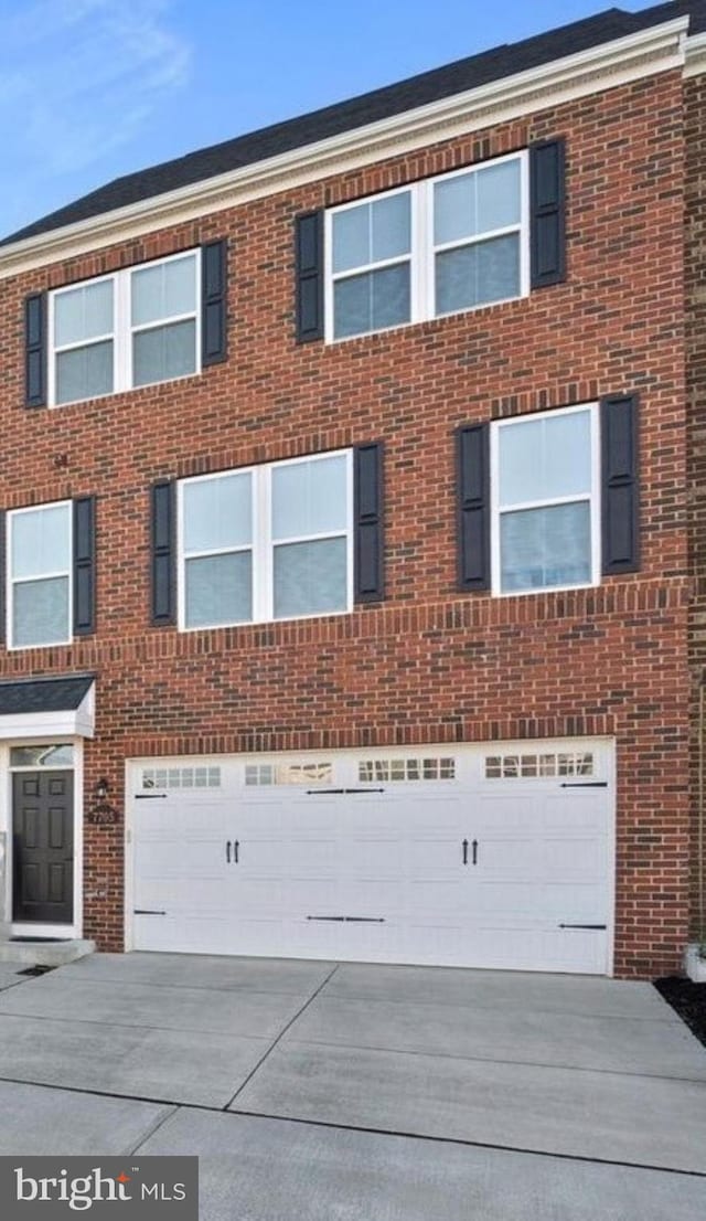 view of property with brick siding, concrete driveway, and an attached garage