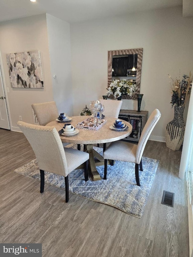 dining area featuring visible vents, baseboards, and wood finished floors