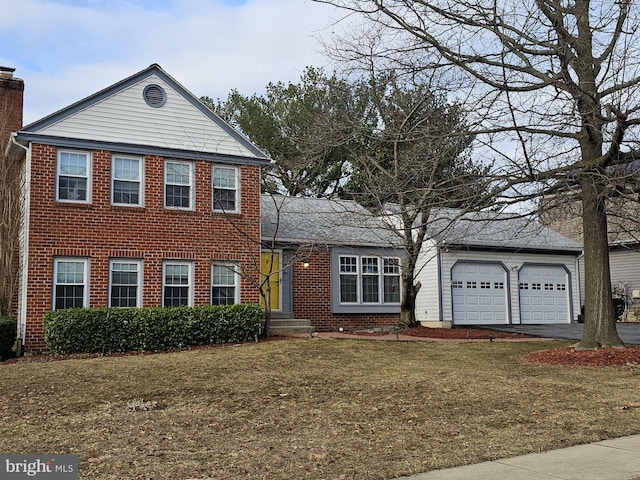 view of front of property featuring a front yard, a chimney, a garage, aphalt driveway, and brick siding