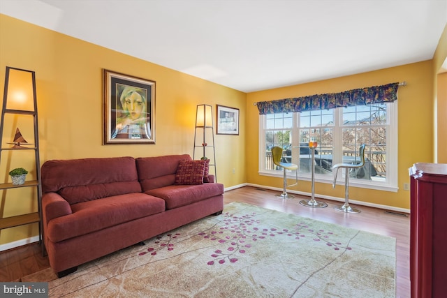 living area featuring wood finished floors, baseboards, and visible vents