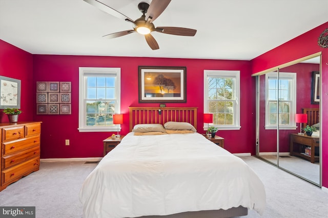 carpeted bedroom featuring multiple windows, baseboards, a closet, and ceiling fan